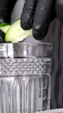 Limonata yapmak, yaz içkisi, soğuk içecek, sağlıklı sıvı. Yaz eldiveni içinde salatalık suyu yapmak eldivenler pişirmek salatalıktan meyve suyu sıkmak cam pişirme lüksüne salatalık koymak