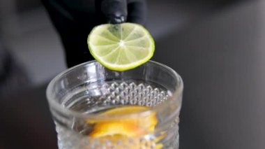 Bardakta limonata, yaz içeceği, soğuk içecek, sağlıklı sıvı limon yapan siyah eldivenli bir limon şefiyle bardağa çarptı.