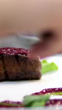 Beyaz tabakta lezzetli ördek filetosu, vişne sosu serpiştirilmiş, güveçte bamyayla servis ediliyor.