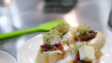 Restorandaki mutfakta yeşillikle dekore et. Peynirli ve jambonlu açık büfe sandviçler için lezzetli atıştırmalıklar. Jambonlu sandviç üzerine sos dök.