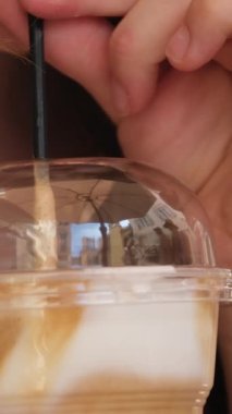 Kız pipetle buzlu latte içiyor.