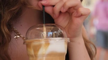 Kız pipetle buzlu latte içiyor.