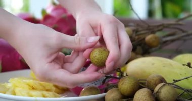 picking longan, local fruit in thailand, to eat from plate on table