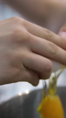 Yumurta kırıyorum. Kırık bir yumurtayı tutan kadın eller. Yumurta kırıyorum. Siyah arka plan. Yavaş çekim.