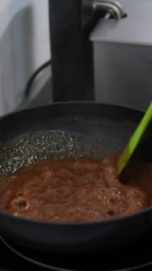 Aşçı sıcak bir tavada beyaz şekeri karıştırdı. Şeker erir ve karamelize olur. Evde tatlı pişirme süreci. Kızartma tavasında karamel