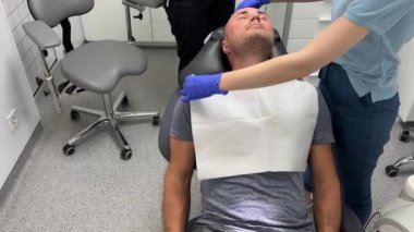 Dişçi koltuğuna uzanmış, pembe önlük giymiş, dişçi dişçiye giden, diş aletlerini kontrol eden pembe eldivenler takan, maske takan ve üniforma giyen hastaya tepeden bakıyorduk. Diş hekimliği kavramı 