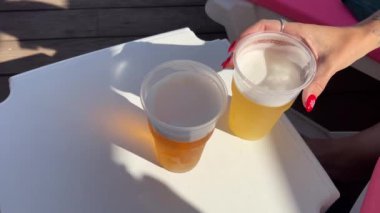 Plajda plastik bir bardakta bira iyi bir havada masada iki bardak rahatlama yüzme. Havuz kenarında