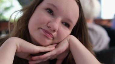 Genç kız başını olumlu bir şekilde sallar, dudaklarını birbirine bastırır ve elleriyle yüzünü destekler. Zorla kabul ettirmek. üzgün gözler yuvarlak yüz