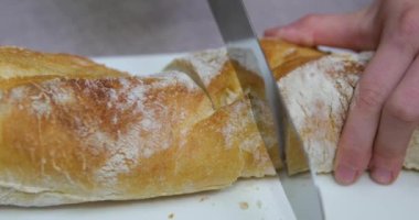 Peynir için dilimlenmiş Fransız ekmeği dilimliyorum. Mutfaktaki Ekmek 'i kesiyorum. Sabah Kahvaltısı hazırlıyorum. Masada taze ekmek var. Fransız ekmeği kesiyorum. Pandispanya için buğday ekmeği.