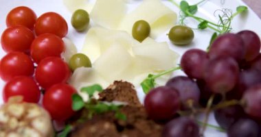 Çeri domatesli, üzümlü ve zeytinli dilimler halinde peyniri dilimleyin. Restoranda peynir servisi.