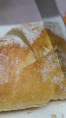 Peynir için dilimlenmiş Fransız ekmeği dilimliyorum. Mutfaktaki Ekmek 'i kesiyorum. Sabah Kahvaltısı hazırlıyorum. Masada taze ekmek var. Fransız ekmeği kesiyorum. Pandispanya için buğday ekmeği.