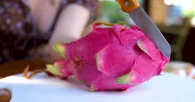 Pitahaya meyvesini muz yaprağı üzerinde siyah bir bıçakla keserken ya da beyaz etli ejderha meyvesiyle keserken, bir parça kestim. Sağlıklı beslenme konsepti. Beslenme, diyet, vejetaryen gıda konsepti.