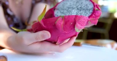 Pitahaya meyvesini muz yaprağı üzerinde siyah bir bıçakla keserken ya da beyaz etli ejderha meyvesiyle keserken, bir parça kestim. Sağlıklı beslenme konsepti. Beslenme, diyet, vejetaryen gıda konsepti.