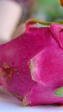 Pitahaya meyvesini muz yaprağı üzerinde siyah bir bıçakla keserken ya da beyaz etli ejderha meyvesiyle keserken, bir parça kestim. Sağlıklı beslenme konsepti. Beslenme, diyet, vejetaryen gıda konsepti.