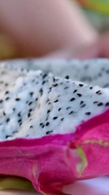 Meyve salatası yapmak için kırmızı ejderha meyvesi soyulan bir kız. Yavaş çekim