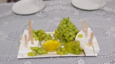 Krem peynirli peynir ve bir restoranda balla servis edilen üzümler. Ahşap şişler lezzetlidir. pahalı
