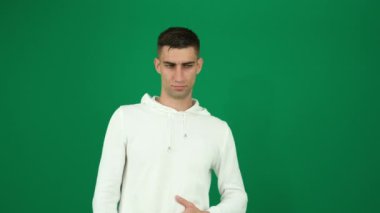 Yeşil arka plandaki yakışıklı bir adamın duyguları. Koyu renk, yakın plan, genç adam. Yanlış anlayan adam nahoş duyguları silkeleyip başını kaşıyacak.