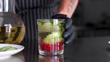 Kadın ellerinin içme bardağına aşılanmış detoks suyu döktüğü yakın plan. Limon, salatalık ve bitkilerden oluşan bir kokteyl ile sağlıkla ilgilenmek tanınmaz hale geldi. Sağlıklı yaşam tarzı.