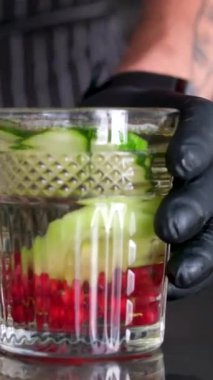 Kadın ellerinin içme bardağına aşılanmış detoks suyu döktüğü yakın plan. Limon, salatalık ve bitkilerden oluşan bir kokteyl ile sağlıkla ilgilenmek tanınmaz hale geldi. Sağlıklı yaşam tarzı.