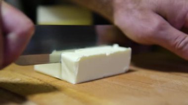 Donmuş yağ. Taze tereyağını tahta arka planda bıçakla kes..