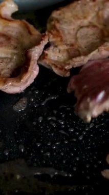 Baharatlı biftek pişirme süreci ve ahşap mutfak masasında otlar, üzerine deniz tuzu ve biber serpiştirme süreci. Adım adım, bir adam biftekleri doğruyor ve kızartma tavasında kızartıyor.