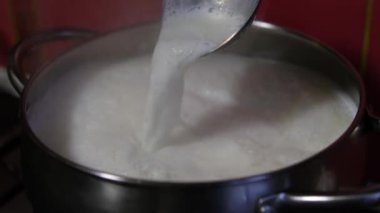 İnekler sütü tencerede kaynatıyor. Kadın tencerede süt karıştırıyor. Süt tencerede kaynamış.