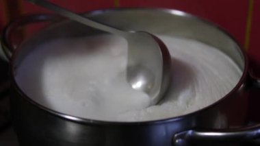 Süt kaynıyor, buhar çıkıyor. Paslanmaz çelik bir kapta süt kaynatmak. Süt kaynamak üzere. Kaynayan süt tavadan gaz sobasına akar. Su ısıtıcısında süt sağılmış inekler. 4K