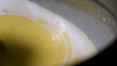 Aşçı, cam kasede kaymak karışımını karıştırmak için kaşık kullanır.