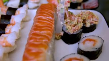 Erkek aşçılar eldiven takmış, aynalı masaya suşi koyuyorlar. Geleneksel Japon mutfağı. İç mekanda lezzetli suşi servisi yapan şefin yakın çekimi. Suşi yap.