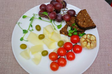 Beyaz bir tabağa siyah biber peyniri serpin. Üzümlü, kirazlı, domatesli. Lezzetli taze peynir ve filizlenmiş yeşillikler. mikroyeşiller
