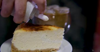 Cheesecake diliminin üzerine çikolata sosu dökülüyor. Çikolata soslu San Sebastian cheesecake dilimi. Kremalı cheesecake