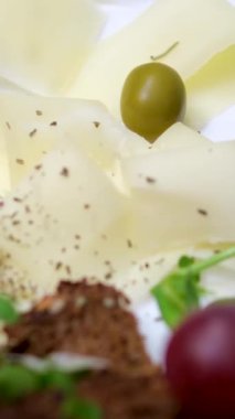 Beyaz bir tabağa siyah biber peyniri serpin. Üzümlü, kirazlı, domatesli. Lezzetli taze peynir ve filizlenmiş yeşillikler. mikroyeşiller