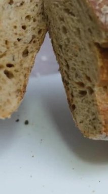 Koyu ahşap arka planda ekşi ekmek dilimliyorum. Ekmeği bıçakla kesmenin yavaş hareketi. siyah ekmek