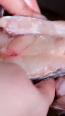 Ev hanımlarının elleri terbiye edilmiş ve sıcak yağla dolu bir tavaya konmuş yayın balığının elleri kızarır ve kızgın yağda kızarır. yayın balığı filetosu kızart