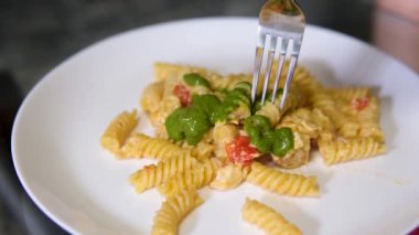 Fusilli makarna, fesleğen sosu ve çatalla fesleğen yaprağı yemek. Pesto soslu makarna çatalla yenir.