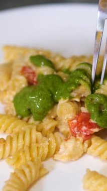 Fusilli makarna, fesleğen sosu ve çatalla fesleğen yaprağı yemek. Pesto soslu makarna çatalla yenir.