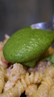 Mavi kasedeki fusilli makarnaya pesto sosu ekle.