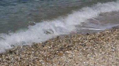 Dağlardan gelen güçlü açık deniz rüzgarları dalgaları ve deniz püskürtülerini çakıl taşlı plajlardan uzaklaştırıyor. Akdeniz çakıl taşları Yunanistan Mikonos 'a temiz su dalgaları