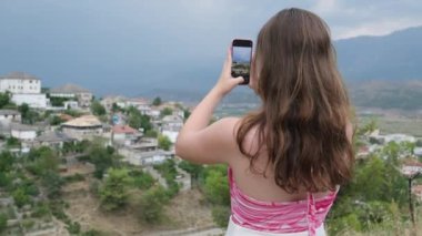 UNESCO, Arnavutluk 'un güneyindeki Cirokastra' daki eski Cirokaster kasabasını listeledi. Kız arka planda Avrupa 'dan gelen turistlerin fotoğraflarını çekiyor. seyahat günlüğü