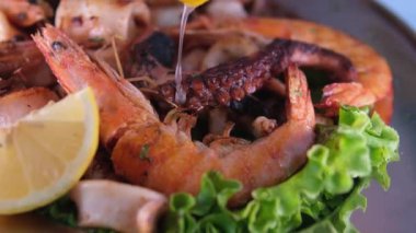 Siyah eldivenli karides ahtapot kadın aşçı kömür ızgarasında kızartılmış somon bifteğinin üzerine taze sıkılmış limon suyu döker. Deniz ürünlerinin üzerine limon dök.