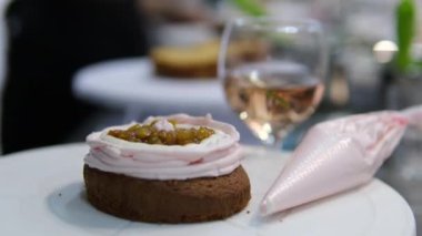 Kadın elleri pembe kremayı güzel bir pembe pastadaki spatulayla aynı seviyeye getiriyor. Kürsüdeki bir kız için doğum günü pastası. Pembe pasta yapan kız.