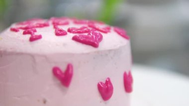 Kadın elleri pembe kremayı güzel bir pembe pastadaki spatulayla aynı seviyeye getiriyor. Kürsüdeki bir kız için doğum günü pastası. Pembe pasta yapan kız.