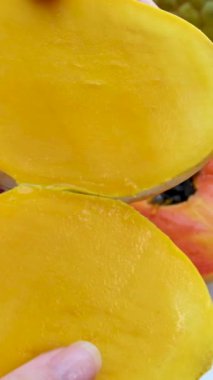 Kadın eli, olgun mangoyu keskin bir bıçakla beyaz bir tabakta küp şeklinde keser.