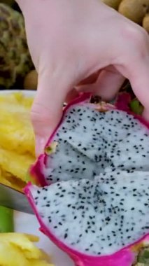Pitahaya meyvesini muz yaprağı üzerinde siyah bir bıçakla keserken ya da beyaz etli ejderha meyvesiyle keserken, bir parça kestim. Sağlıklı beslenme konsepti. Beslenme, diyet, vejetaryen gıda konsepti.