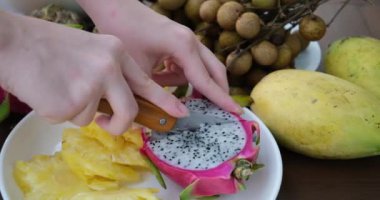Pitahaya meyvesini muz yaprağı üzerinde siyah bir bıçakla keserken ya da beyaz etli ejderha meyvesiyle keserken, bir parça kestim. Sağlıklı beslenme konsepti. Beslenme, diyet, vejetaryen gıda konsepti.