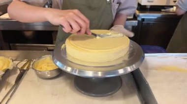 Kremi kenarlara yay. Pasta şeflerinin spatulasına yakın çekim. Bir kadın pasta ve hamur işi hazırlar. Kürsüyü eliyle çeviriyor. Yavaş çekim videosu. 