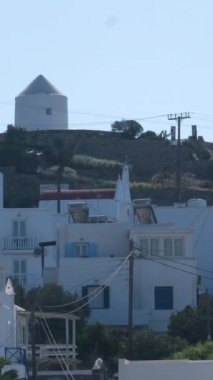Meşhur yel değirmenleriyle Mykonos kasabası manzarası ve yaz günü tekneleri ve yolcu gemisi olan liman manzarası. Mykonos, Cyclades adaları, Yunanistan. Kamera tavasıyla