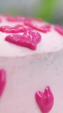 Kadın elleri pembe kremayı güzel bir pembe pastadaki spatulayla aynı seviyeye getiriyor. Kürsüdeki bir kız için doğum günü pastası. Pembe pasta yapan kız.