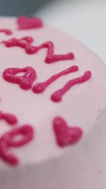 Kadın elleri pembe kremayı güzel bir pembe pastadaki spatulayla aynı seviyeye getiriyor. Kürsüdeki bir kız için doğum günü pastası. Pembe pasta yapan kız.