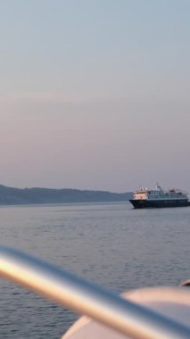 Güneşli bir yaz gününde denizde ya da okyanusta seyahat eden yolcu gemisi. Lüks yolcu gemisinin havadan görünüşü. Gemi deniz dağlarında gün doğumu günbatımı pembe gökyüzü mavidir. Denizde gemi